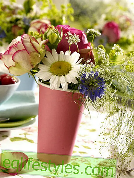 Table d'été avec des fleurs dans des gobelets en papier